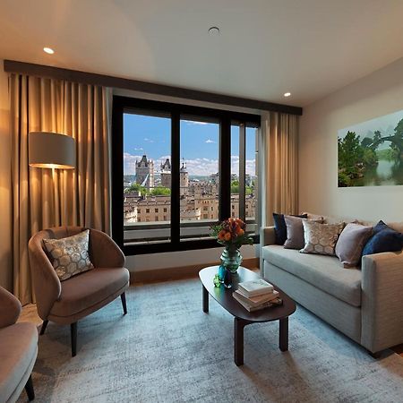 Tower Suites By Blue Orchid Londra Exterior foto The photo depicts a modern living room with a contemporary design. It features two stylish, circular chairs and a comfortable sofa adorned with various decorative pillows. A small coffee table is positioned in front of the sofa, topped with books and