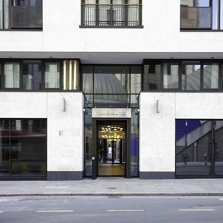 Tower Suites By Blue Orchid Londra Exterior foto The image shows the entrance of a modern building, characterized by its minimalist architectural design. The facade features a combination of large glass windows and smooth stone surfaces. The entrance is framed by glass doors, flanked by stylish lig