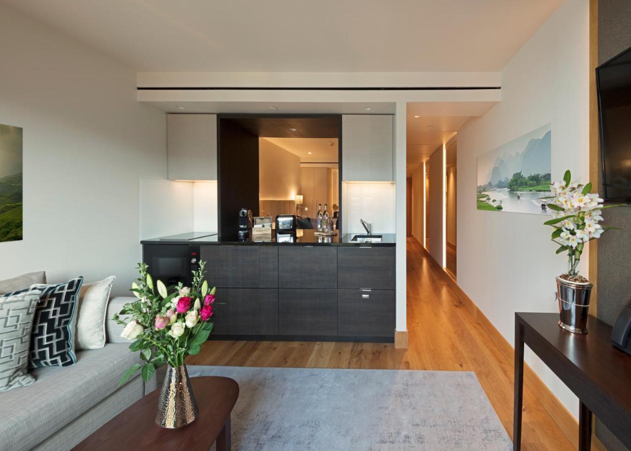 Tower Suites By Blue Orchid Londra Exterior foto The photo showcases a modern and stylish interior space, likely a living area of a luxurious apartment or hotel suite. 

- **Bar Area**: There is a sleek bar counter that features a variety of bottles and glassware, suggesting a well-equipped space f