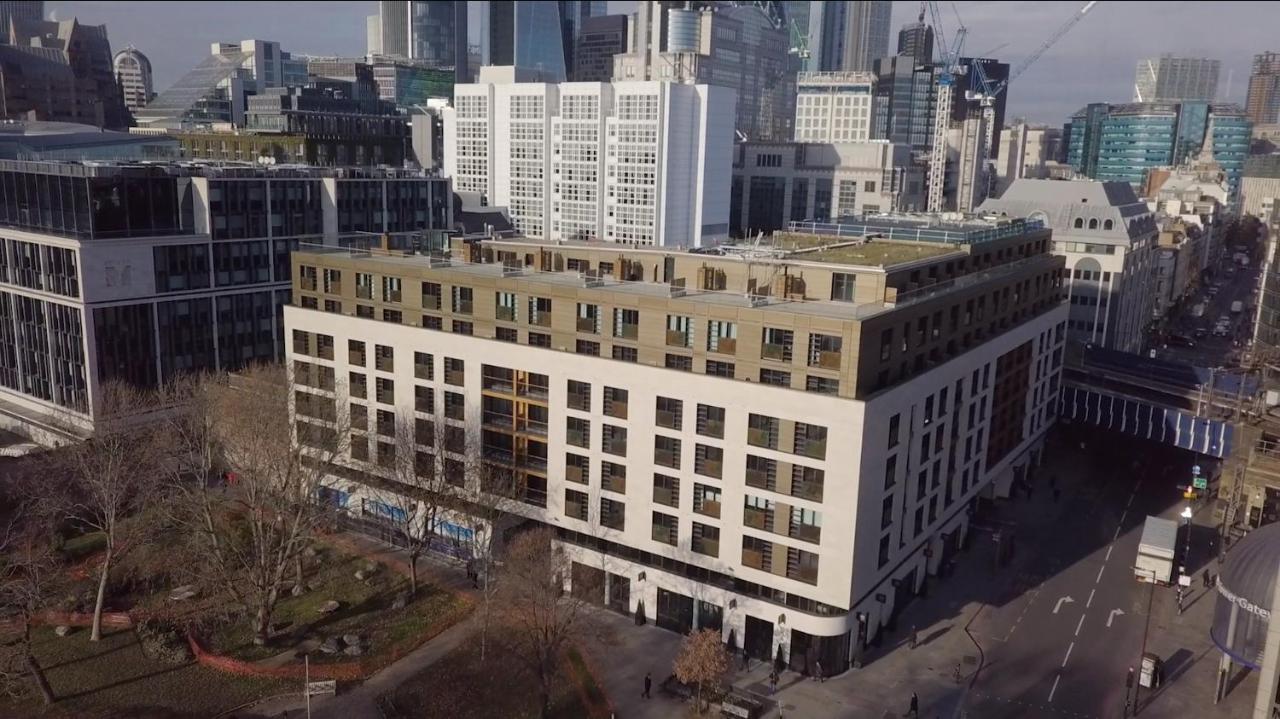 Tower Suites By Blue Orchid Londra Exterior foto The photo shows a large, modern building with a combination of white and light-colored facades. The structure has multiple floors and features a series of square windows, providing a contemporary architectural style. Surrounding the building, there a
